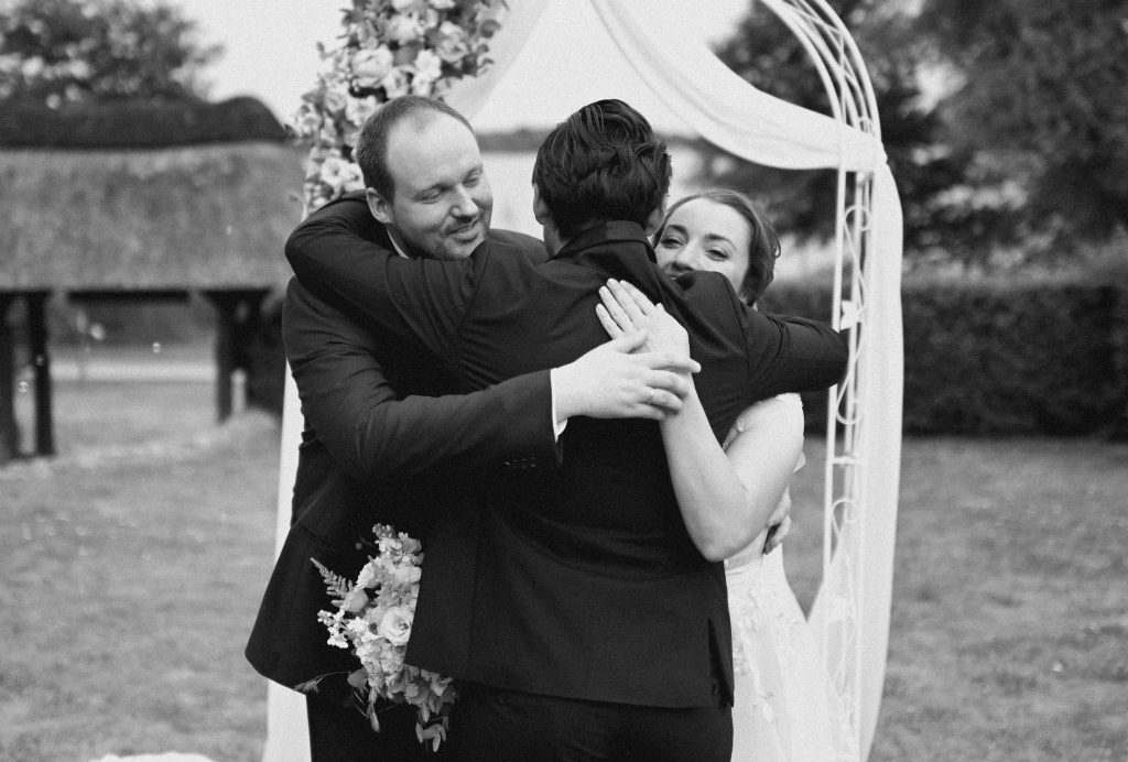Das Brautpaar umarmt Ihren Tamada nach einer Hochzeit