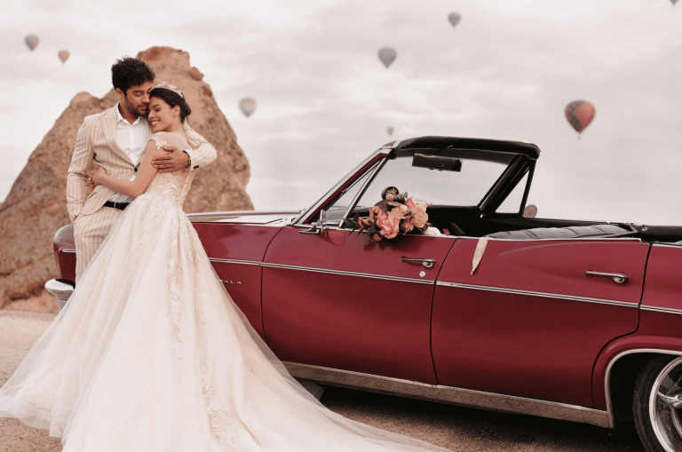 Brautpaar neben einem roten Hochzeitsauto