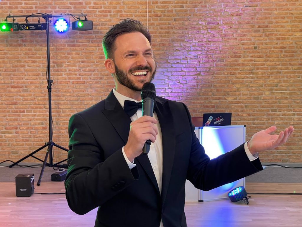 Tamada Tobi lacht bei der Moderation mit dem Mikrofon Tamada Tobi lacht bei der Moderation mit dem Mikrofon