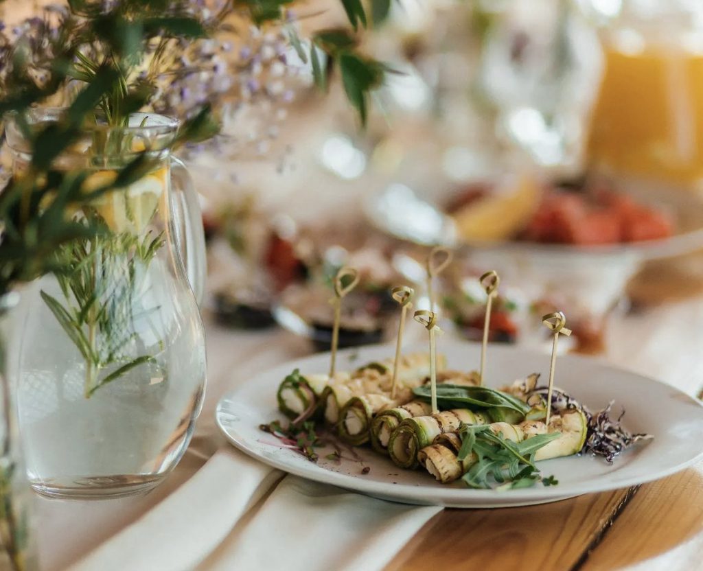 Gerollte Zucchinivorspeisen mit Kräutern auf einer weißen Platte