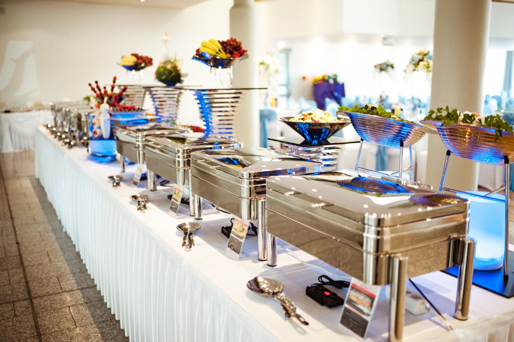 Hochzeitsbuffet mit Warmhaltebehältern, Salaten und dekorierten Obstplatten
