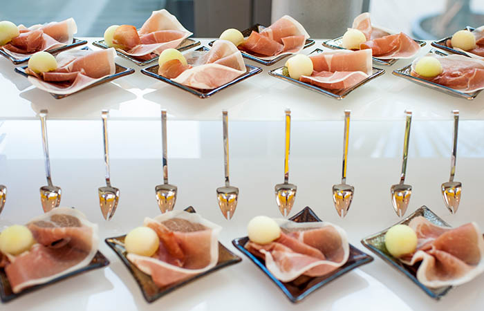 Schinken und Melonenkugeln als einzeln angerichtete Vorspeisen