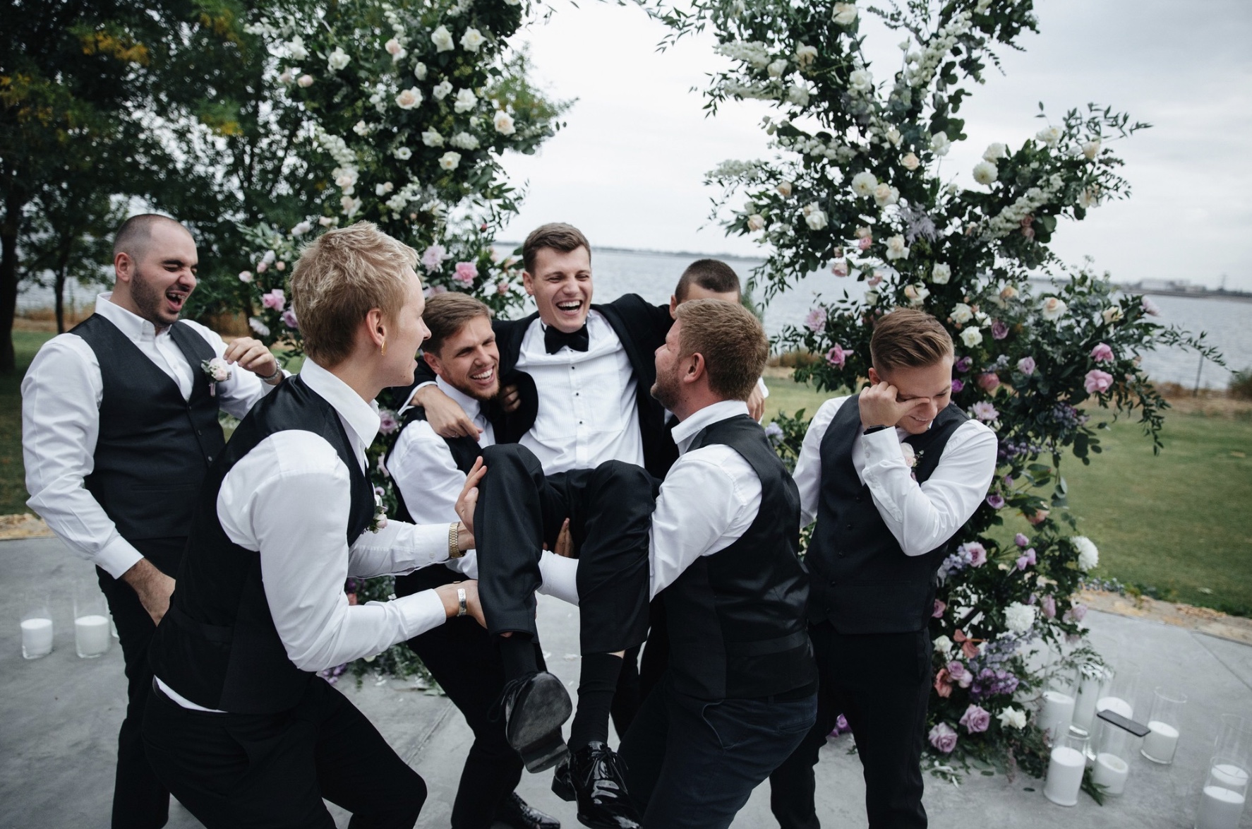 Die Groomsmen werfen den Bräutigam für ein originelles Foto in die Luft – aufgenommen im Park von Schloss Elbroich, voller Spaß und guter Laune.