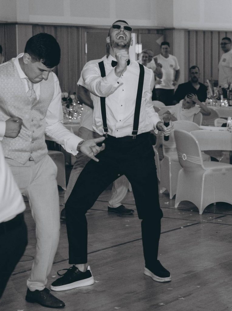 Hochzeitsmoderator Arti von AlexShow mit Sonnenbrille und Mikrofon tanzt auf der Hochzeitsparty – Schwarz-Weiß-Aufnahme Titel: Hochzeitsmoderator Arti – Party & Stimmung