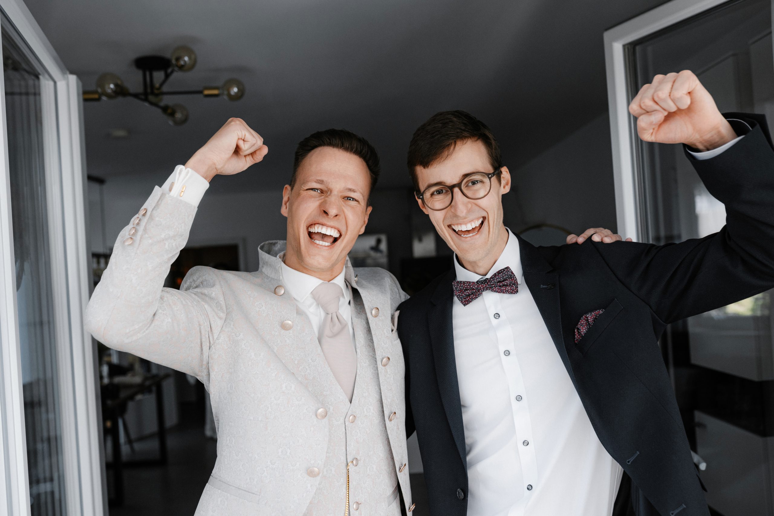 Magnus und ein Begleiter lachen beim Getting-ready mit erhobenen Armen.