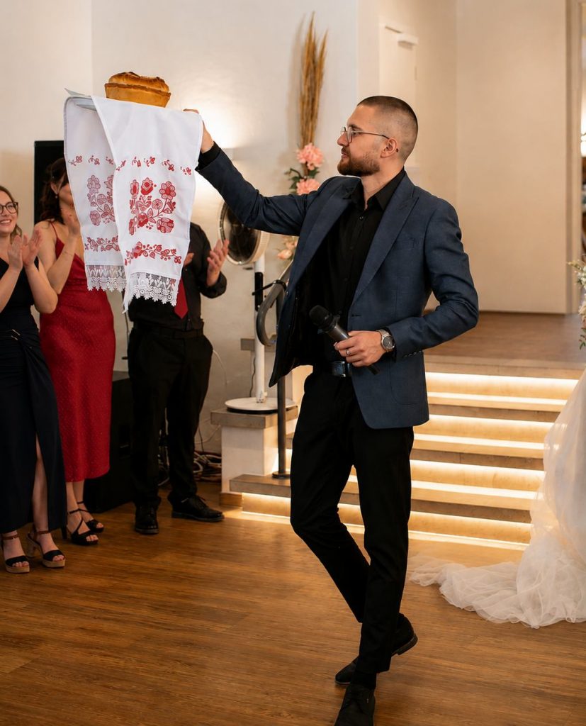 Hochzeitsmoderator Davis präsentiert das traditionelle Hochzeitsbrot auf einem bestickten Tuch während der Brotzeremonie