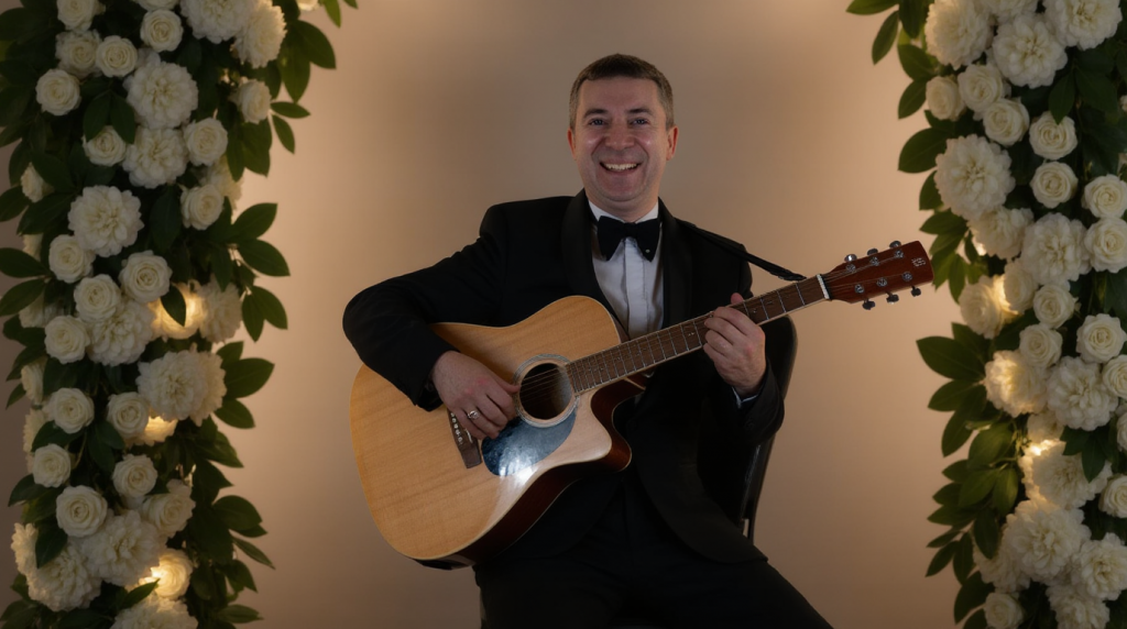 Elias spielt Gitarre zwischen weißen Blumenarrangements