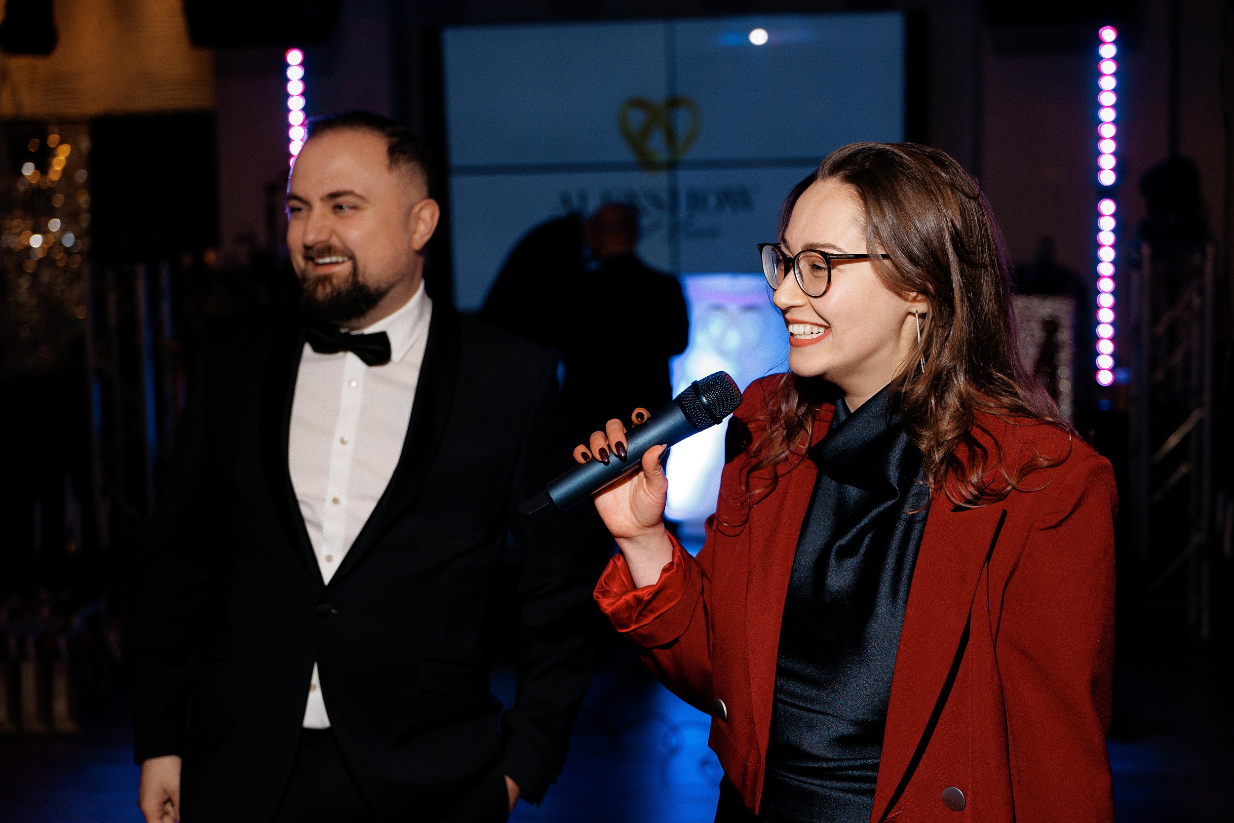 Moderatorin Jane führt durch eine internationale Firmenfeier vor Live-Publikum.