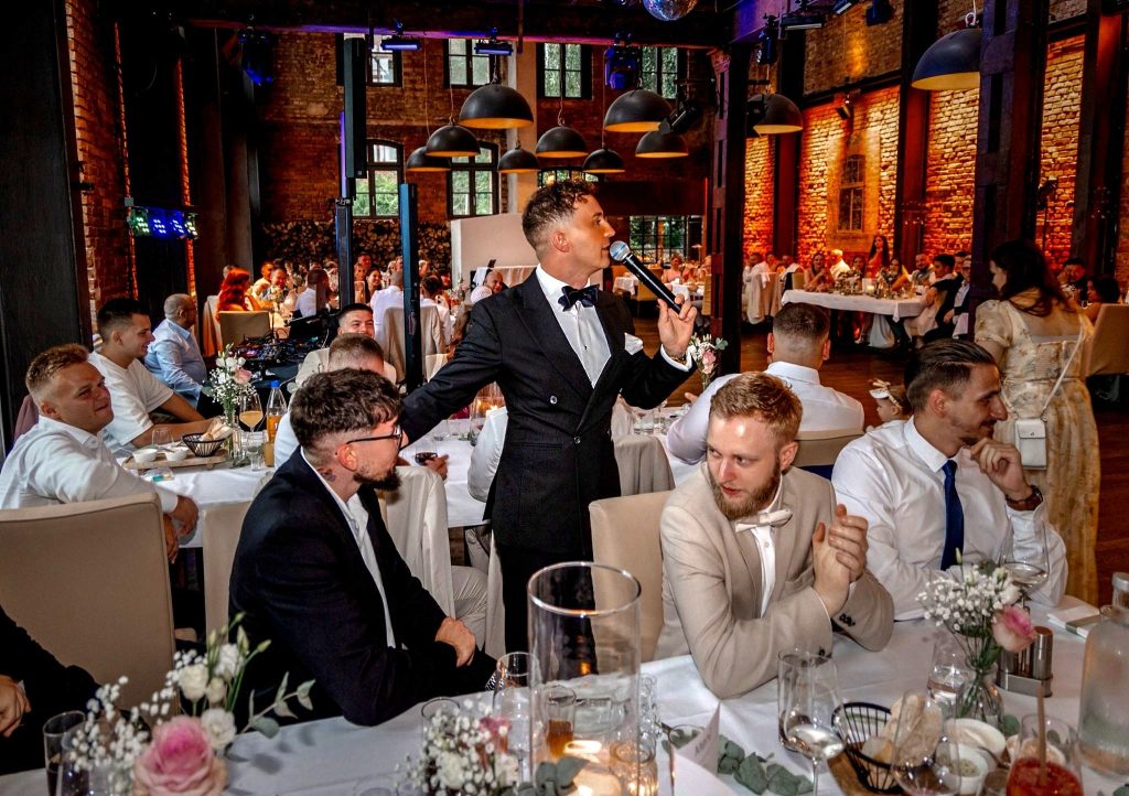 Wedding moderator and Tamada Johann Sky moderating directly among the guests during a wedding reception in Germany.
