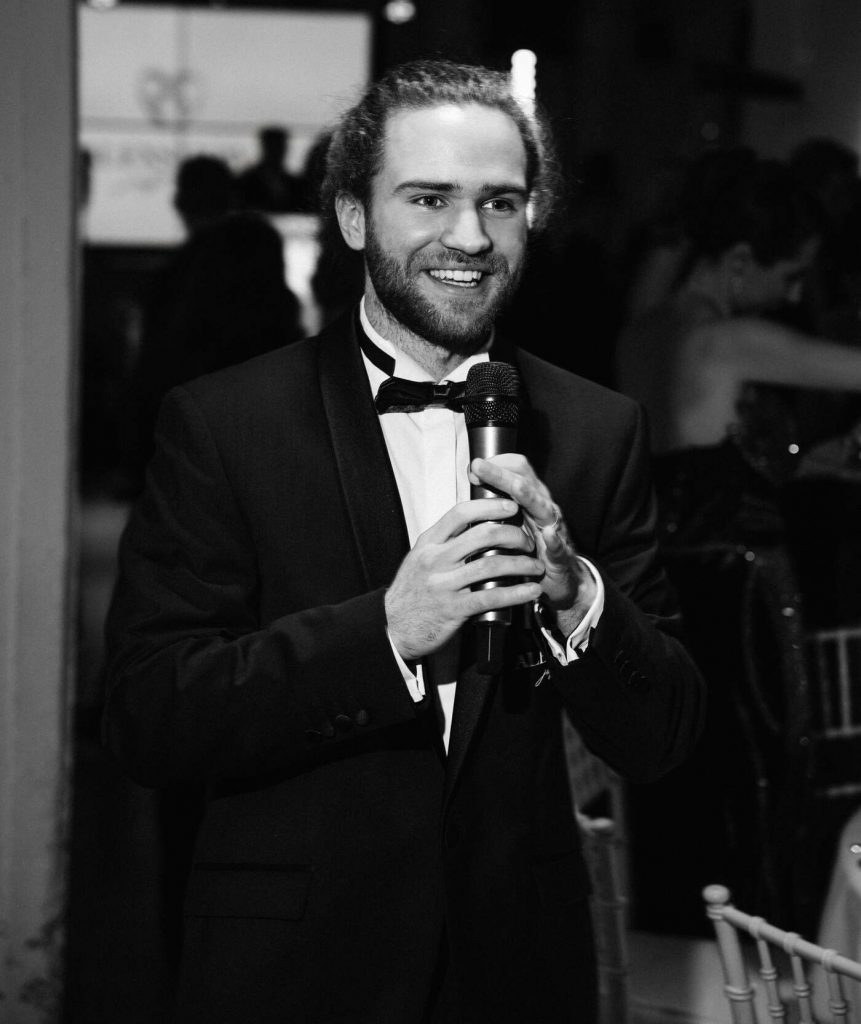 Hochzeitsmoderator Mark in NRW im Smoking mit Mikrofon moderiert eine Hochzeitsfeier