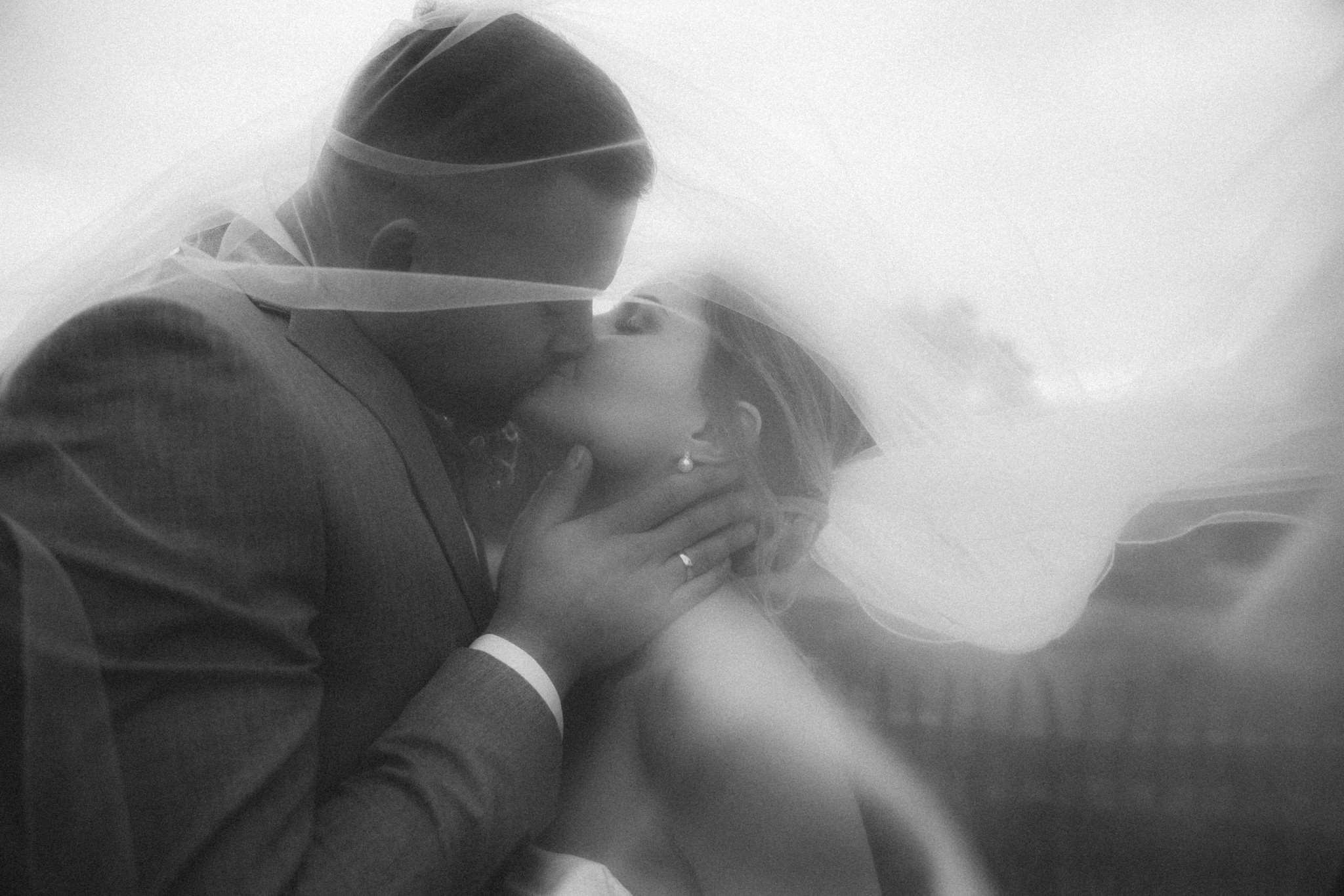 Romantischer Kuss des Brautpaares unter dem Schleier