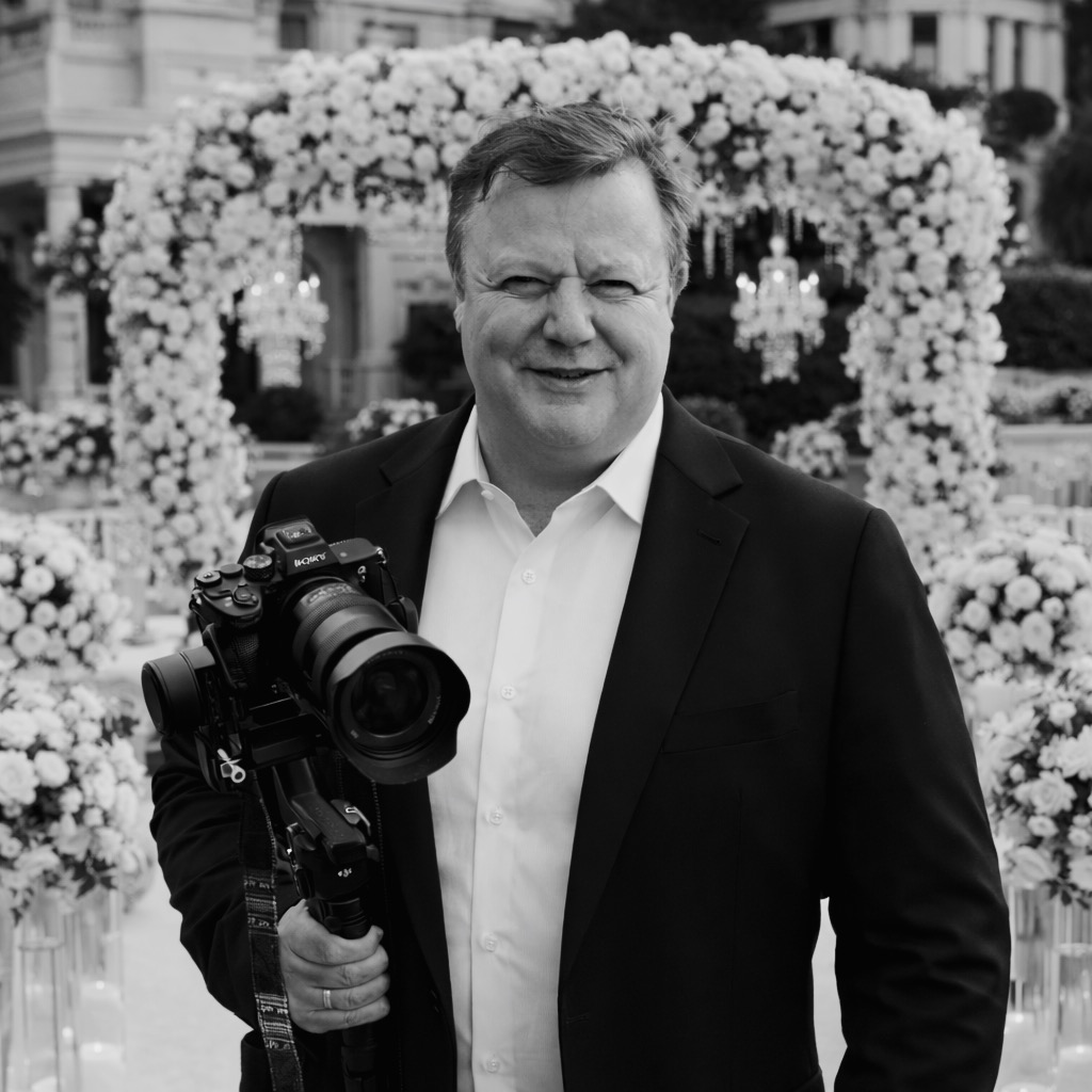 Porträt von Hochzeitsvideograf Oleks mit professioneller Kamera vor eleganter Hochzeitslocation