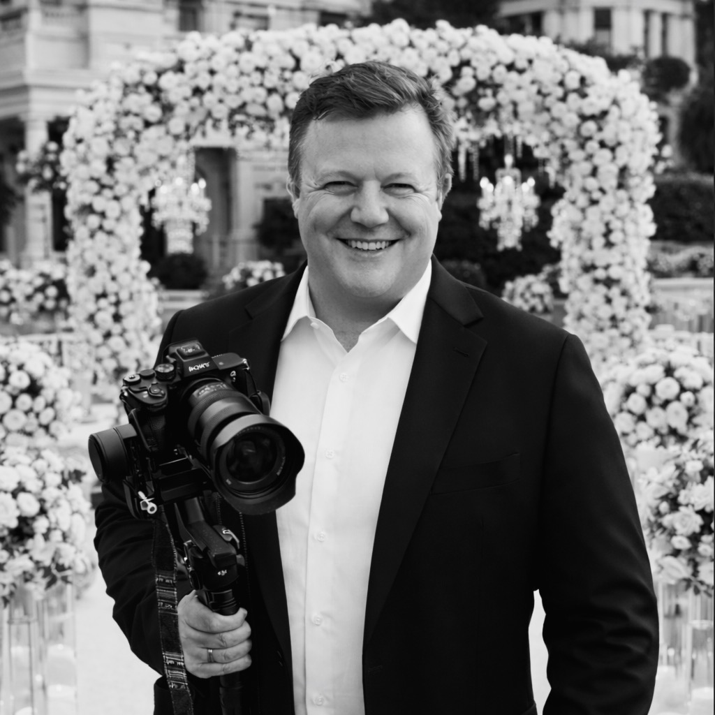 Porträt von Hochzeitsvideograf Oleks mit professioneller Kamera vor eleganter Hochzeitslocation