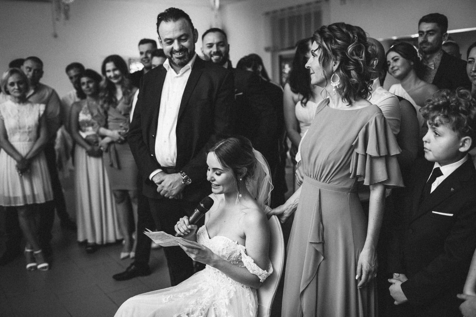 Braut hält eine emotionale Rede vor Familie und Gästen während ein Tamada die Hochzeit begleitet.