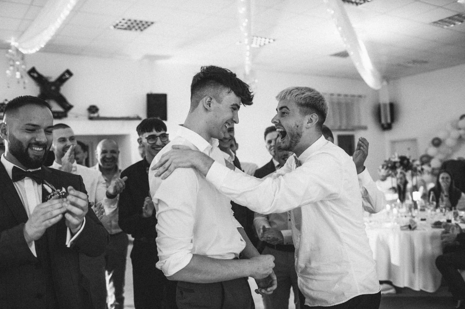 Hochzeitsgäste lachen und feiern emotional während ein Tamada für Stimmung sorgt.