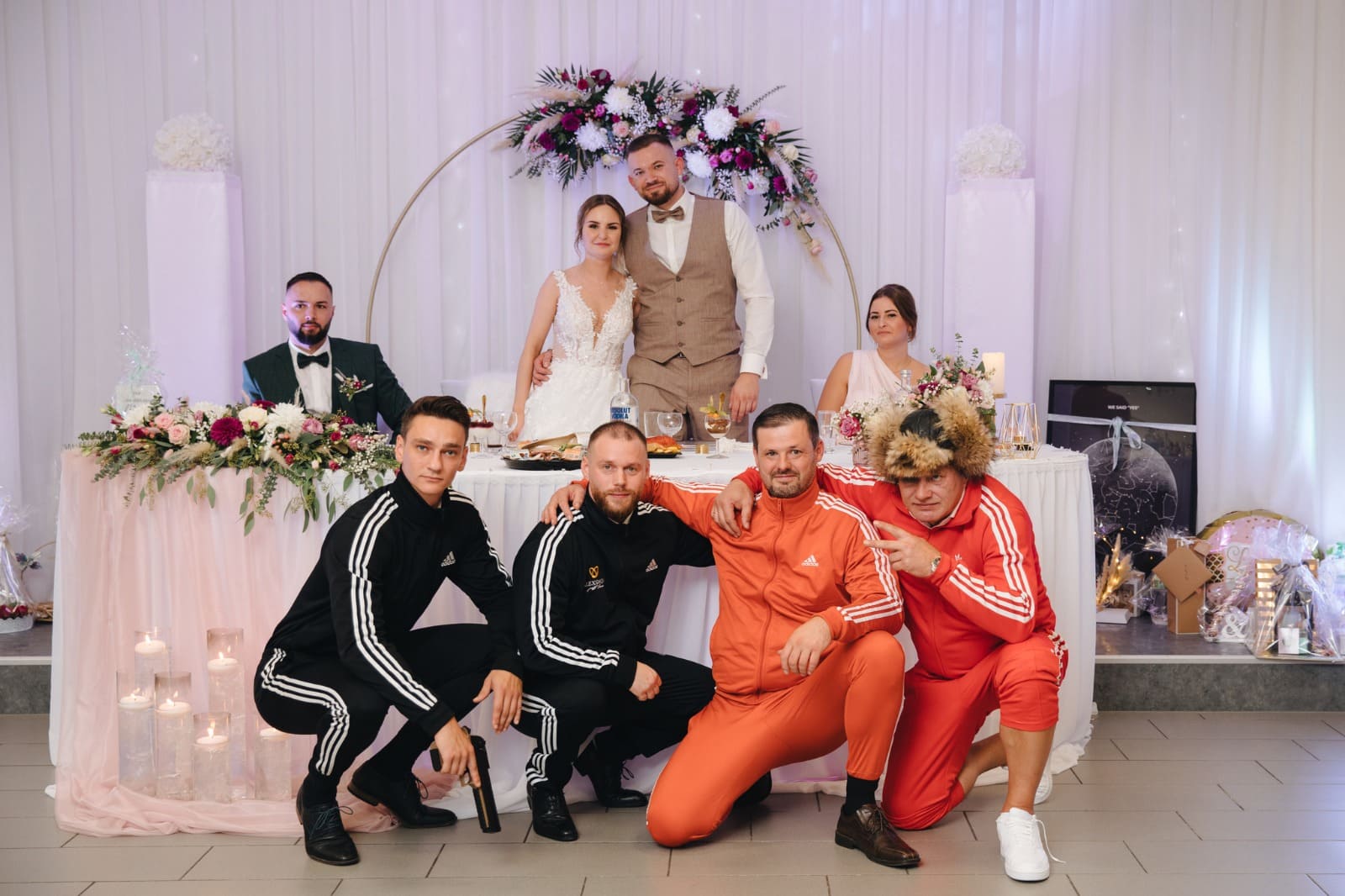 Tamada Hochzeit Gruppenfoto mit Brautpaar und Freunden in Trainingsanzügen.