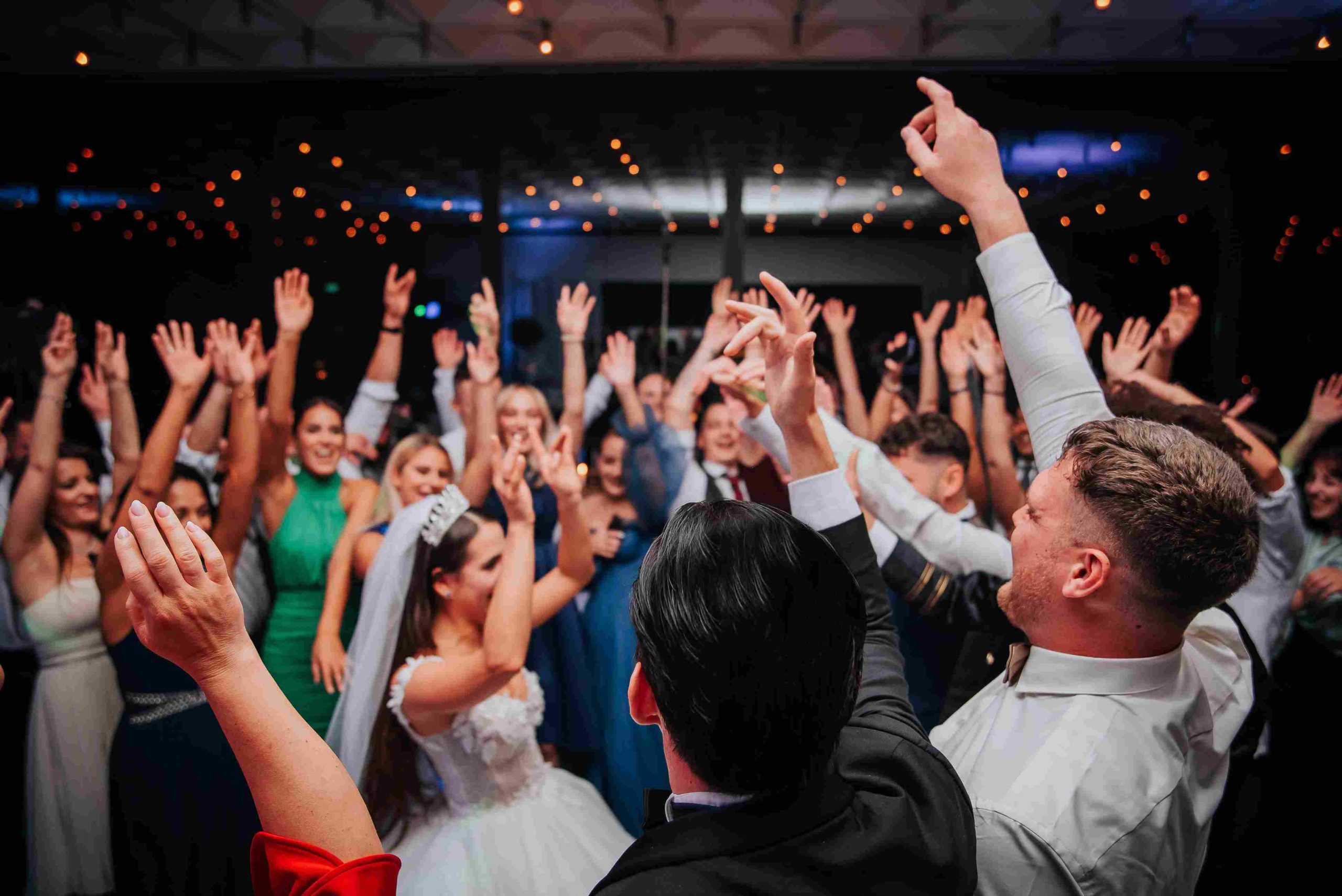 Ein Tamada moderiert eine lebendige Hochzeitsparty mit tanzenden Gästen und Brautpaar