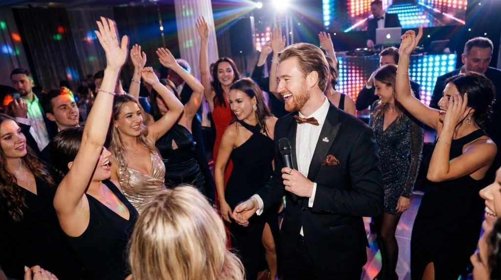 Tamada bei Hochzeitsparty – Moderator mit Mikrofon animiert Gäste auf der Tanzfläche