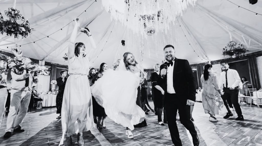 Russischer und deutscher Tamada feiert gemeinsam mit Brautpaar und Gästen auf der Tanzfläche während einer Hochzeit in Deutschland