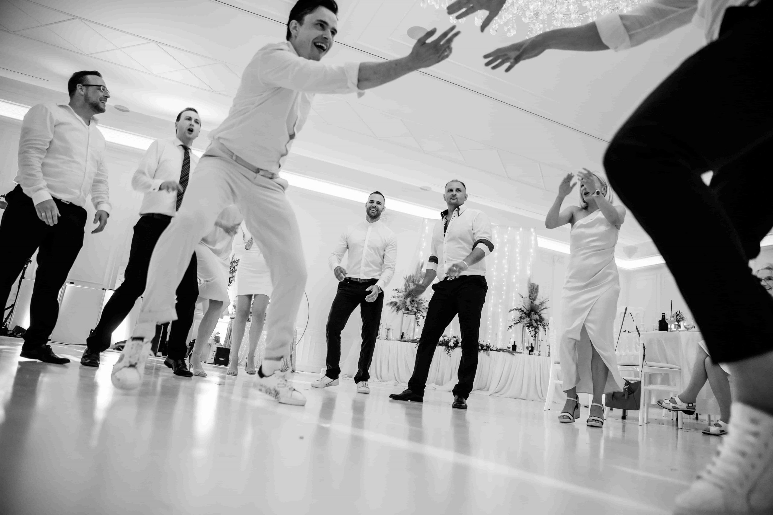 Ausgelassene Party auf der Tanzfläche einer russisch-deutschen Hochzeit in Berlin mit tanzenden Gästen in Schwarzweiß