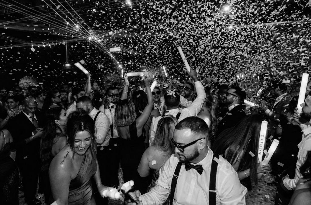 Hochzeitsgäste feiern ausgelassen auf der Tanzfläche einer russisch-französischen Hochzeit, während Konfetti durch die Luft fliegt.