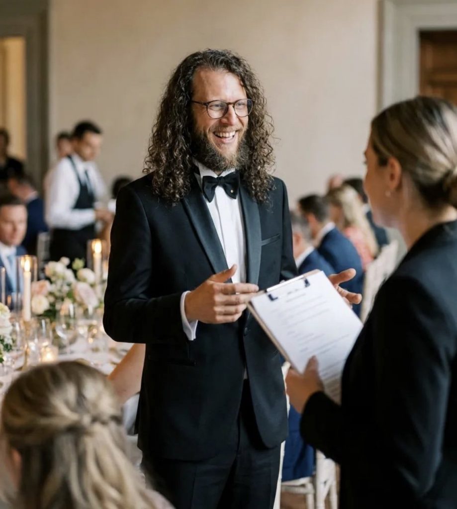 Hochzeitsmoderator Jonny bespricht den Ablauf der Hochzeit mit dem Servicepersonal während der Hochzeitsfeier.