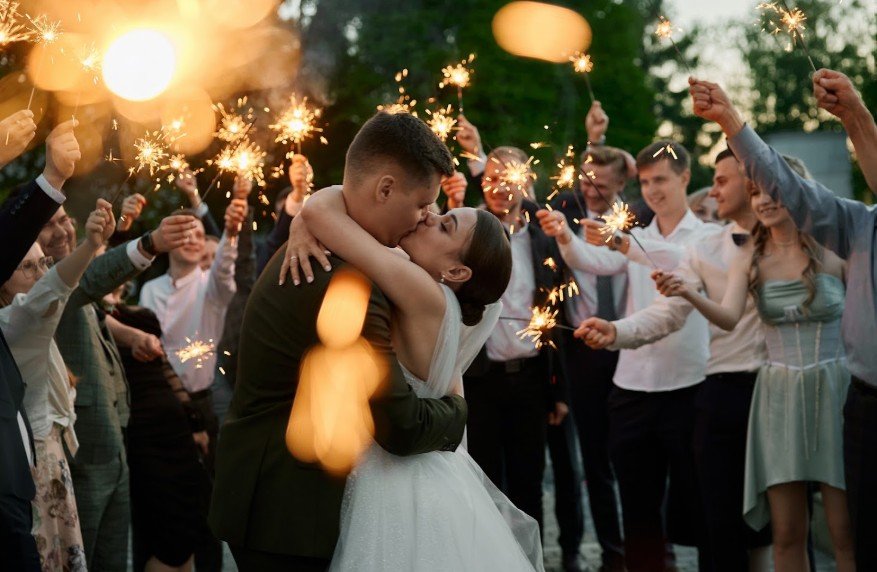 Brautpaar küsst sich am Abend umringt von Gästen mit Wunderkerzen bei der Hochzeit