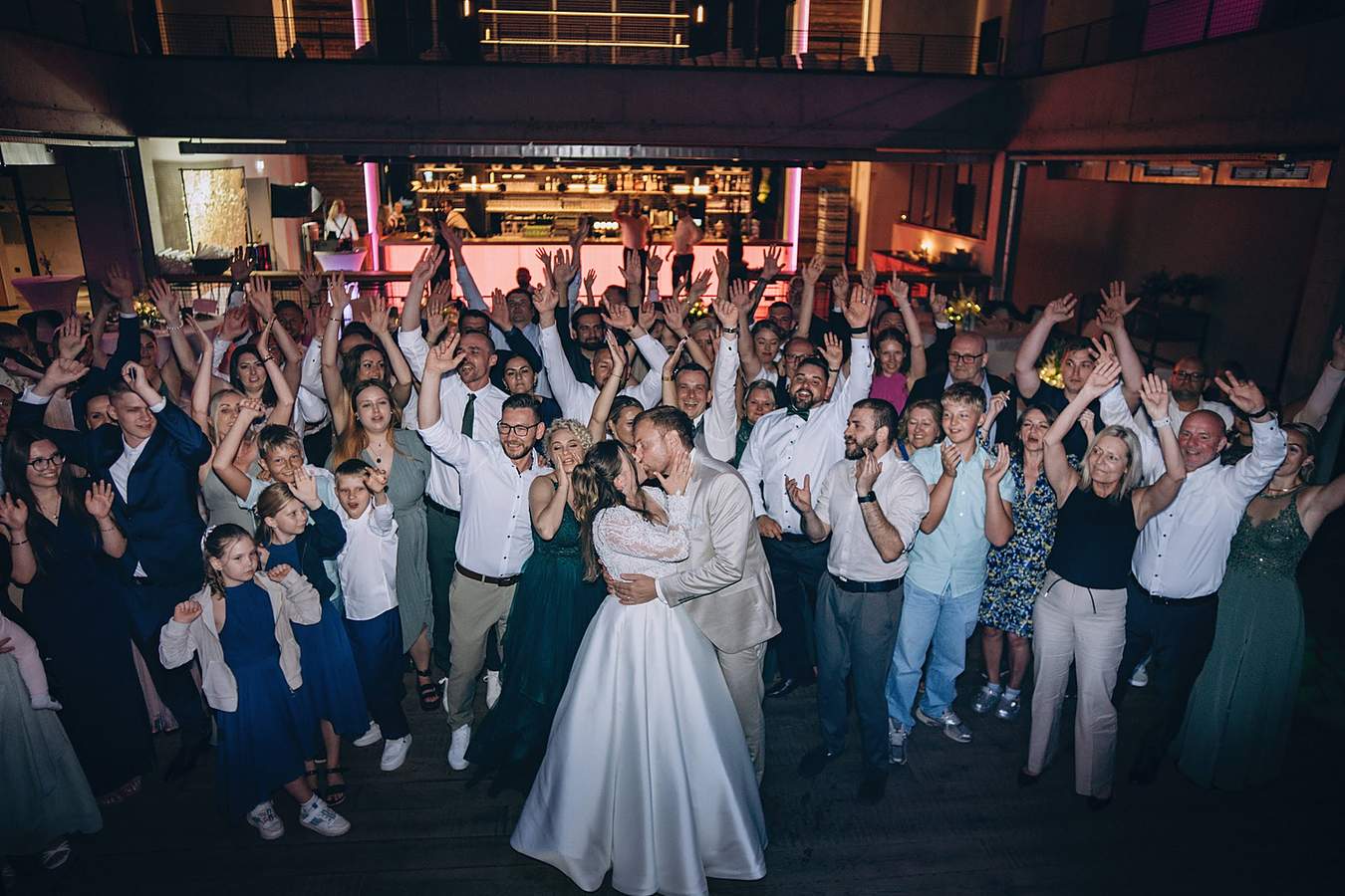 Großes Gruppenbild aller Gäste um das küssende Brautpaar bei einer Hochzeit in Frankfurt