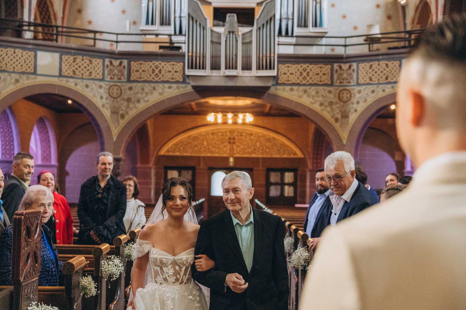 Die Braut wird in der Kirche von einem Begleiter zum wartenden Bräutigam geführt.