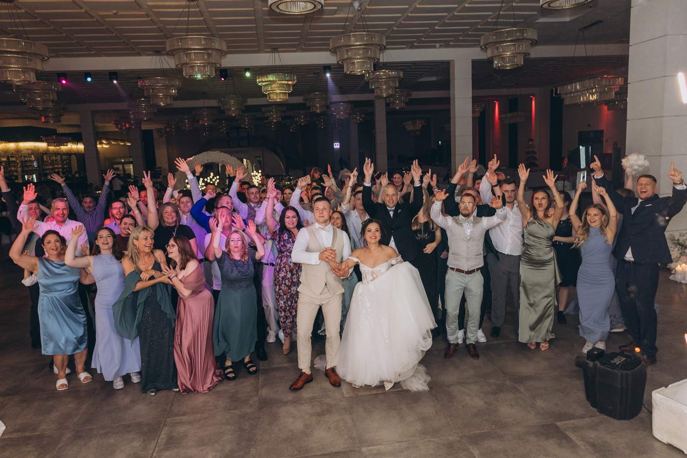 Großes Gruppenfoto aller Gäste um das küssende Brautpaar bei der Hochzeit in Köln