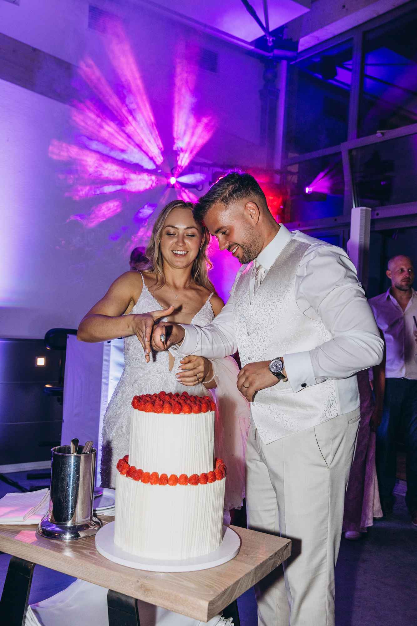 Brautpaar schneidet gemeinsam eine Hochzeitstorte mit Erdbeeren an
