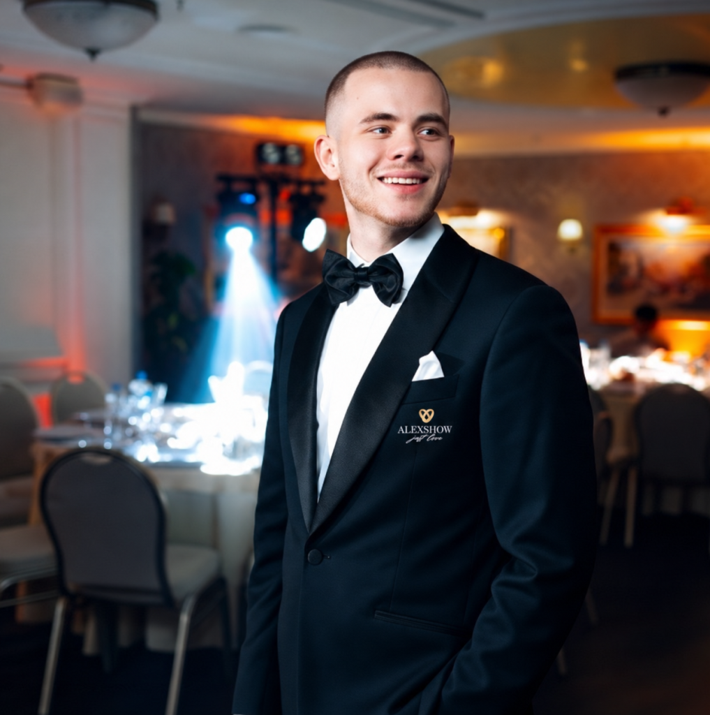 Tamada Luca im schwarzen Smoking mit AlexShow-Logo auf einer Hochzeitsfeier
