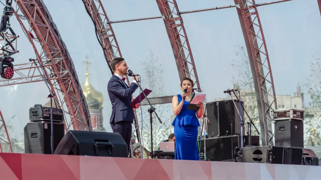 Sergey Solovyov und eine Co-Moderatorin auf einer großen Veranstaltungsbühne.