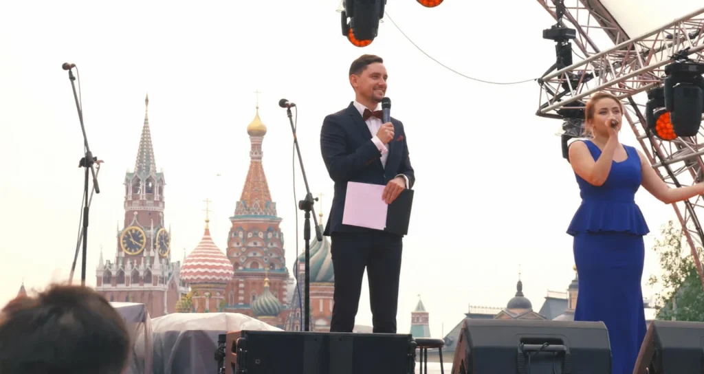 Sergey Solovyov bei einer Bühnenmoderation vor der Kulisse des Roten Platzes in Moskau.